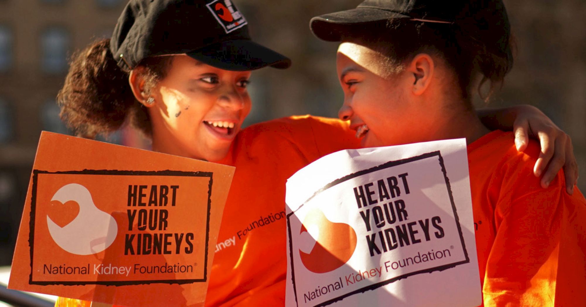 Two people are smiling and holding signs that read 